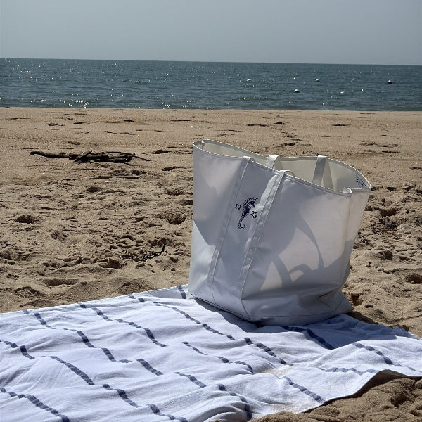 White bag on a sandy beach with ocean and clear sky in the background
