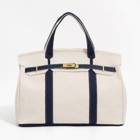 White handbag with navy straps and trim on a white background