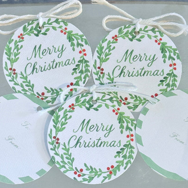 Three 'Merry Christmas' tags with green wreath designs on a white background.
