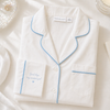 White pajama top with blue piping on a white background