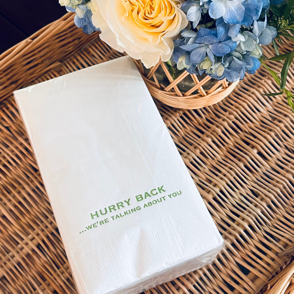 White napkin with text on a wicker surface with flowers