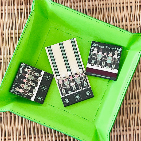 Three decorative cards with black and white designs on a green tray.