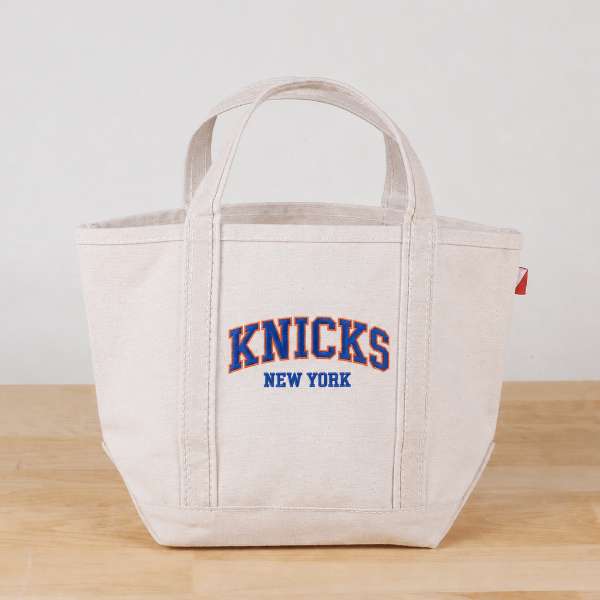 Beige tote bag with 'Knicks New York' text on a wooden surface