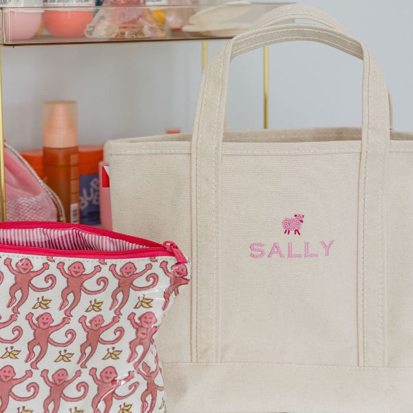 Beige tote bag with 'SALLY' branding on a shelf with beauty products.