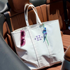 White tote bag with sunglasses and monogram in a car