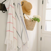 Striped towels hanging on a rack with a basket and hat in a room.