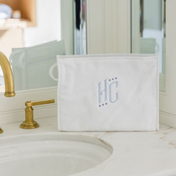 White pouch with 'HC' monogram on a bathroom counter