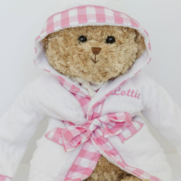 Teddy bear wearing a pink checkered robe with 'Lottie' embroidered on it against a white background