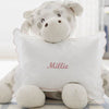 Plush toy cow with a pillow that has 'Millie' embroidered on it, on a light background.