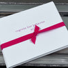 A set of notecards with the text 'regrets her behavior' on the front, sealed with a hot pink ribbon.