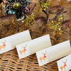 Set of Christmas cards with reindeer designs on a wicker surface with decorative items.