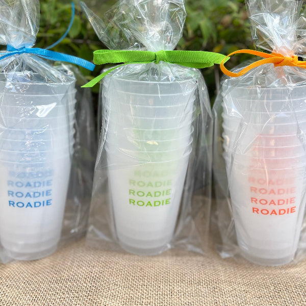 A set of shatterproof plastic cups with 'ROADIE' printed on them, packaged in clear plastic, with each cup tied with a ribbon in different colors.