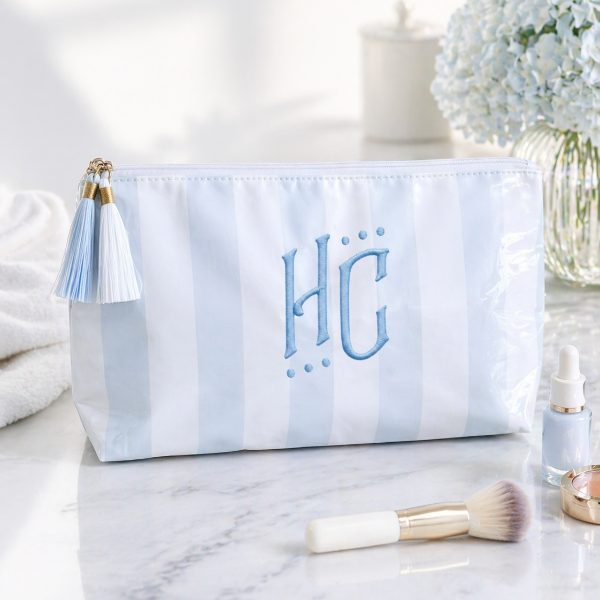 Marble-patterned pouch with 'HC' initials, tassel, and makeup items on a marble surface.