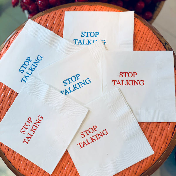 A set of white paper napkins with the text 'STOP TALKING' printed in blue and red ink.